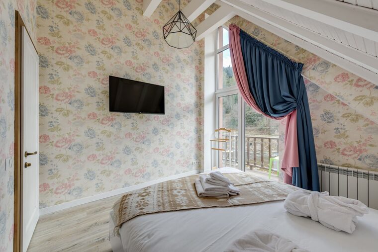 Attic bedroom with soft grey damask wallpaper and exposed wood beams