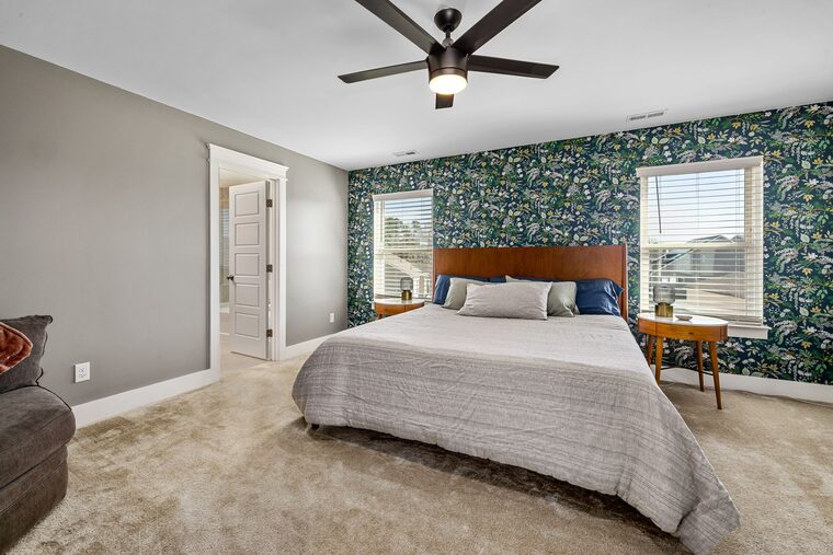 Bedroom with a deep green botanical wallpaper feature wall behind the bed