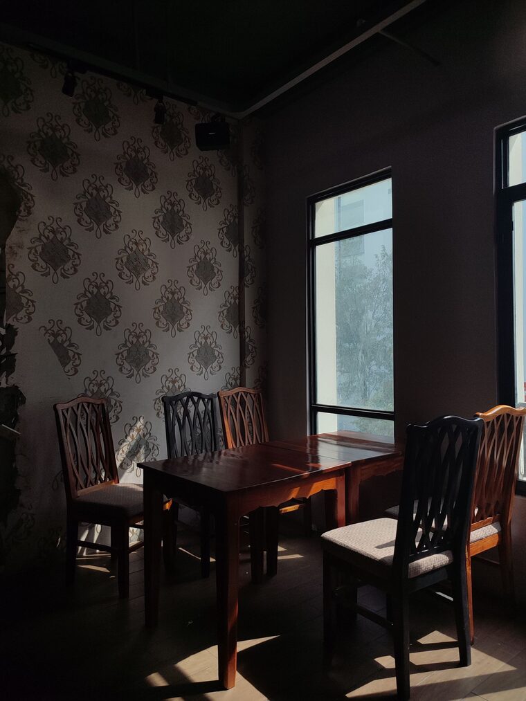 Dining nook with dark damask wallpaper and a wooden table by the window