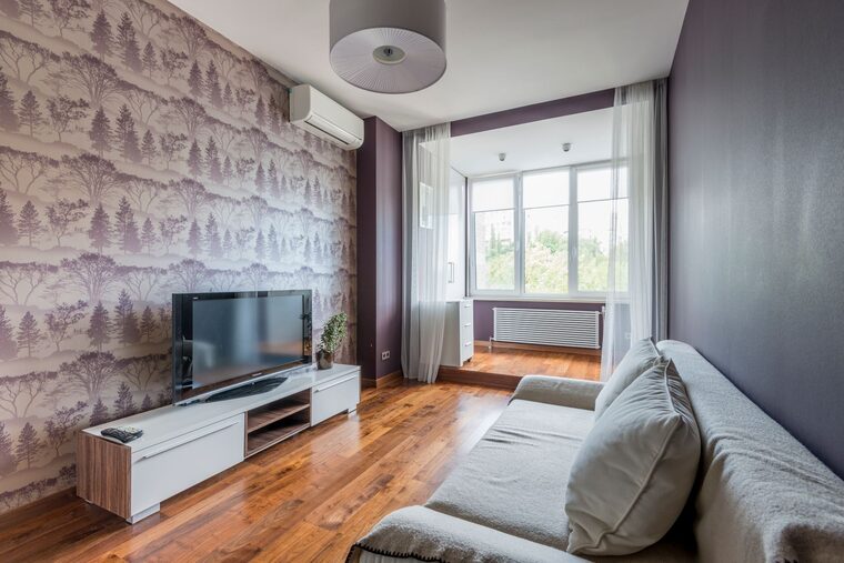 Living room with a botanical forest-pattern wallpaper accent wall behind the media console